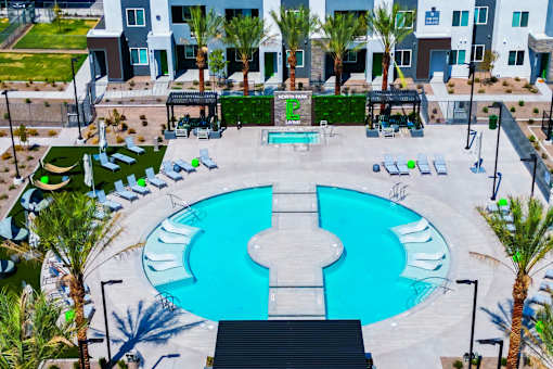 A large blue and white pool surrounded by palm trees and lounge chairs.