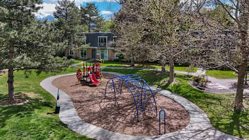 A playground with a blue swing set and red slide.