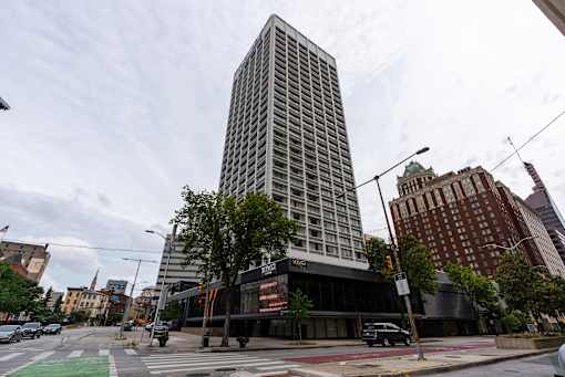A tall building with a glass facade stands in the middle of a city street.