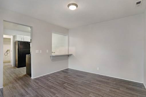 A room with a black fridge and a white wall.