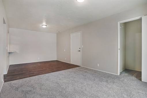 A room with a carpeted floor and two doors.