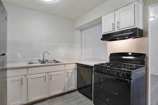 A kitchen with a black stove and white cabinets.