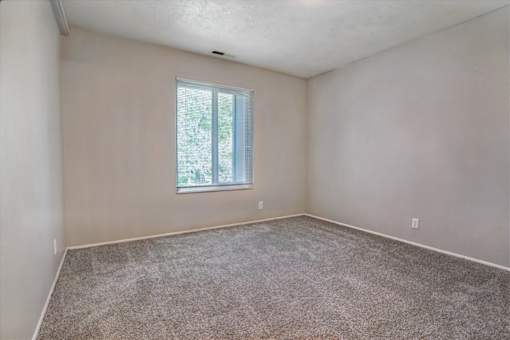 A room with a window and carpeted floor.