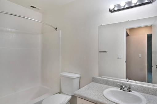 A white bathroom with a toilet, sink, and mirror.