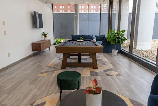 A room with a pool table and a green ottoman.