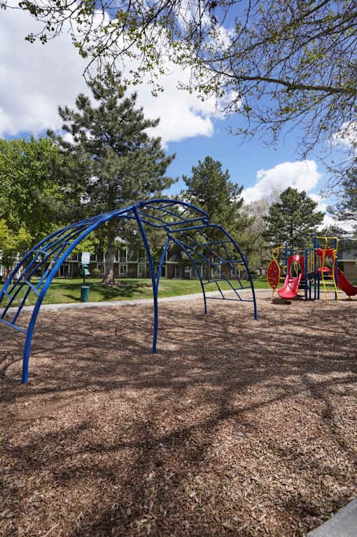 A playground with a blue swing set and red slide.