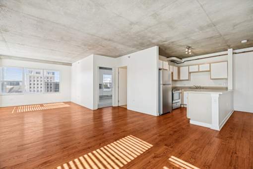 A spacious kitchen and living room with wooden floors and white walls.
