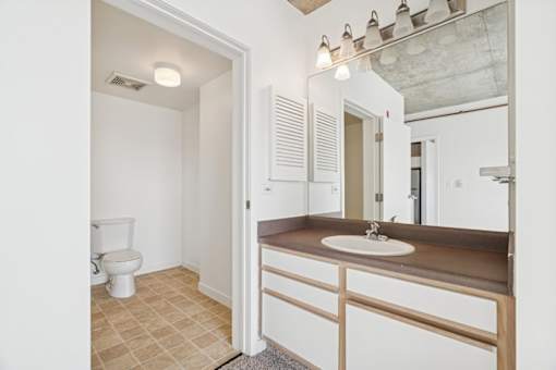 A bathroom with a toilet, sink, and mirror.