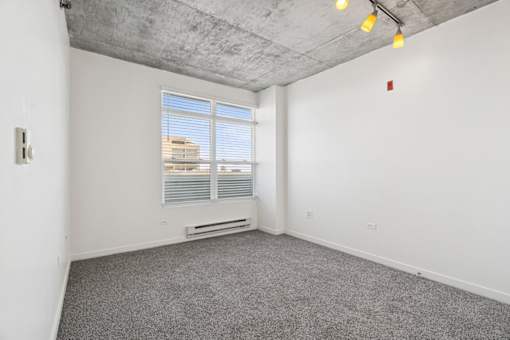 A room with a window and a grey carpet.