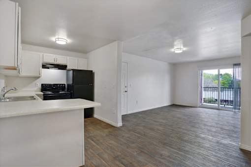 A kitchen with white cabinets and a black fridge.