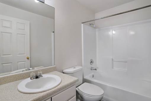 A white bathroom with a sink, toilet, and bathtub.