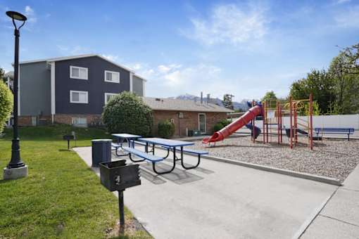 A playground with a slide and a bench in front of a building.
