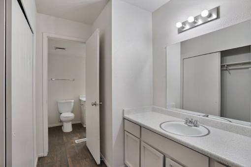 A white bathroom with a toilet, sink, and mirror.