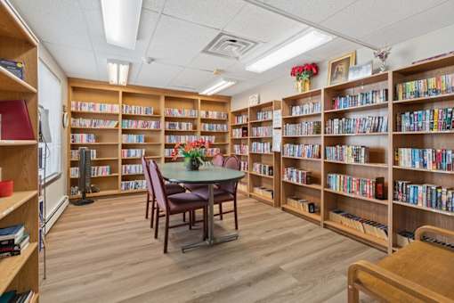 A library with wooden shelves filled with books and a table in the middle.