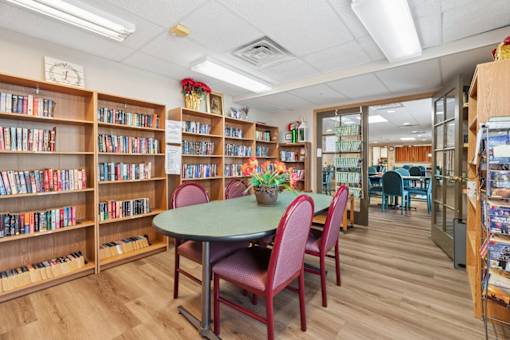 A library with a table and chairs in the middle of the room.