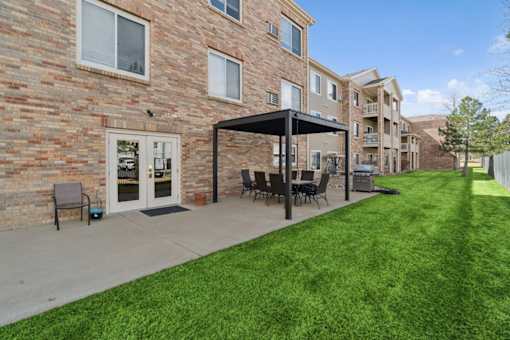 A patio with a table and chairs is in front of a brick building.