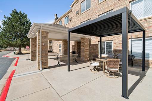A patio with a table and chairs is covered by a black awning.