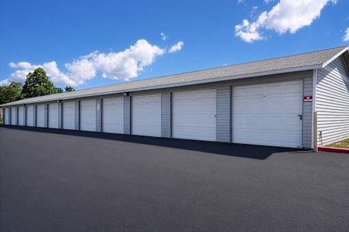 A long building with a grey roof and white garage doors.