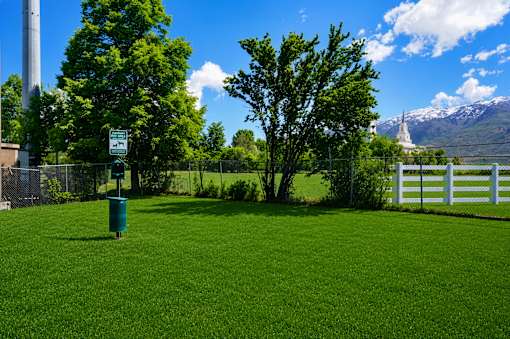 A green grassy area with a sign and a fence.