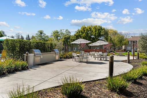 A park with a table and chairs and a trash can.