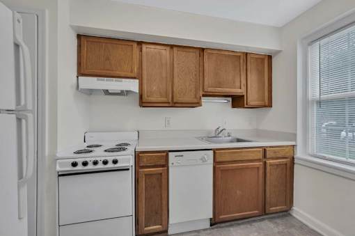 A kitchen with white appliances and wooden cabinets.
