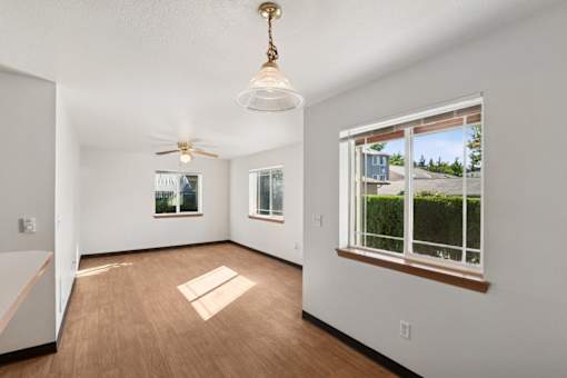 A room with a ceiling fan and a window with a view of a house.