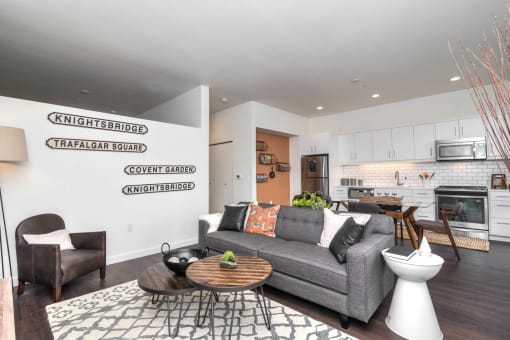a living area with a couch coffee table and a kitchen in the background
