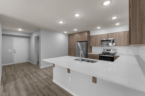 an empty kitchen with a white counter top and a stainless steel stove and refrigerator