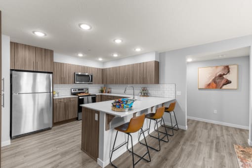 a kitchen with a large island and a stainless steel refrigerator