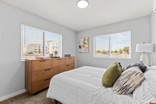 a bedroom with a bed and two windows