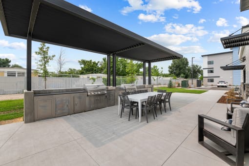 a covered patio with a table and chairs and a grill