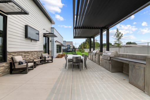 the outdoor patio has a grill and a table with chairs