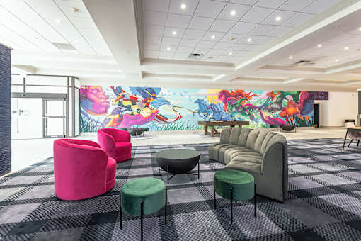 A room with a mural on the wall and a variety of seating options.