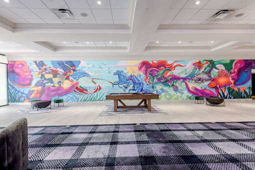 A room with a large mural of colorful sea creatures and a bench in the center.