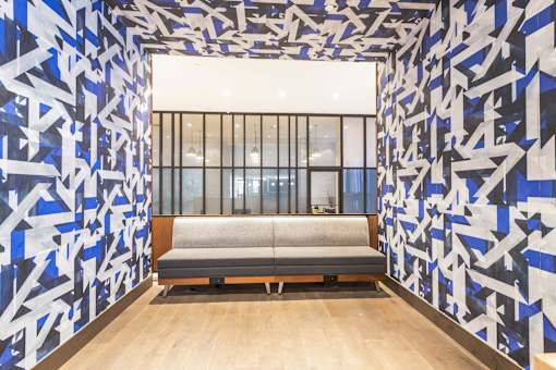 A room with a blue and white patterned wallpaper and a grey bench.