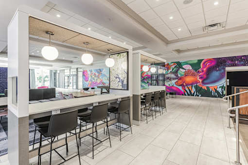 A white table with chairs is in front of a colorful mural.
