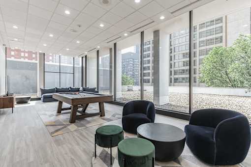 A modern living room with a long table and black chairs.