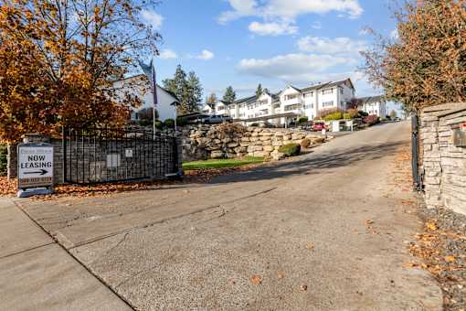 the front driveway of a house with a stone fence and a sign that reads new