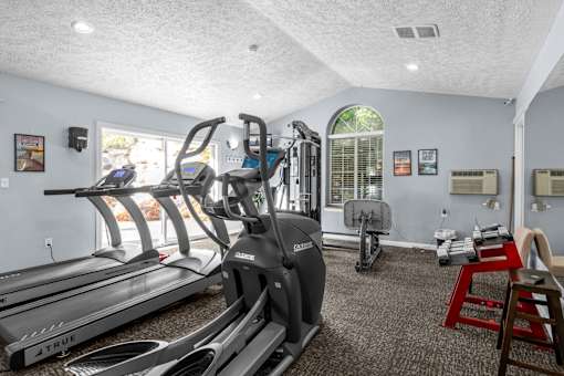 a gym with treadmills and other exercise equipment in a room with a window