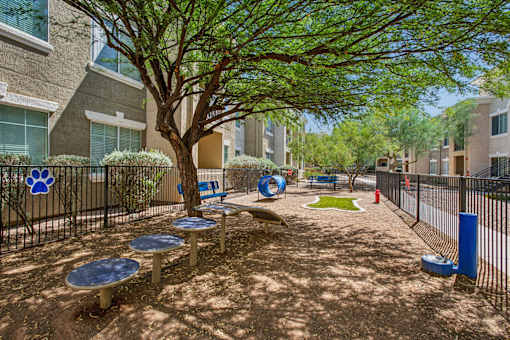 A playground with a blue table and a tree in the middle of a courtyard.