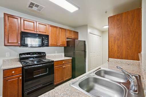 A kitchen with a black stove top oven, a black microwave, and a black refrigerator.