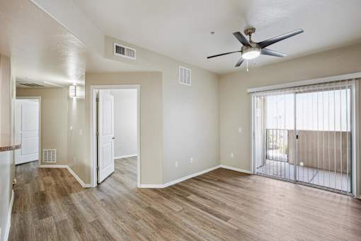 A room with a ceiling fan and sliding glass doors.