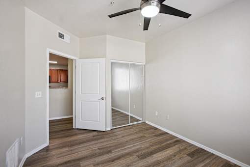 A room with a ceiling fan and a door leading to another room.