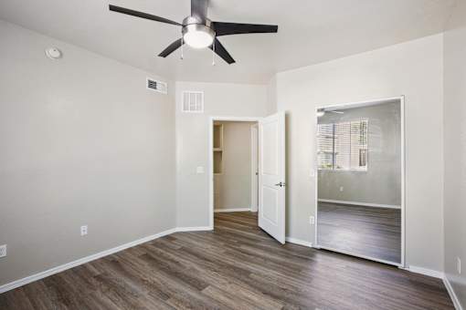 A room with a ceiling fan and wooden flooring.
