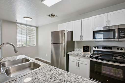 A kitchen with a stainless steel refrigerator, microwave, and oven.
