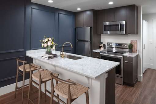 A kitchen with dark blue cabinets and a white marble countertop.