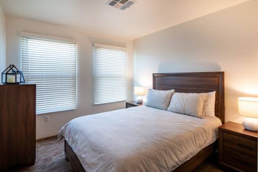 A bedroom with a bed, nightstand, and window blinds.