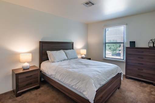 A bedroom with a large bed, nightstands, and a window.