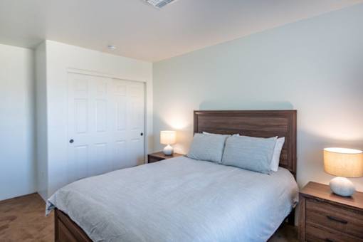 A bedroom with a bed, nightstands, and a door.