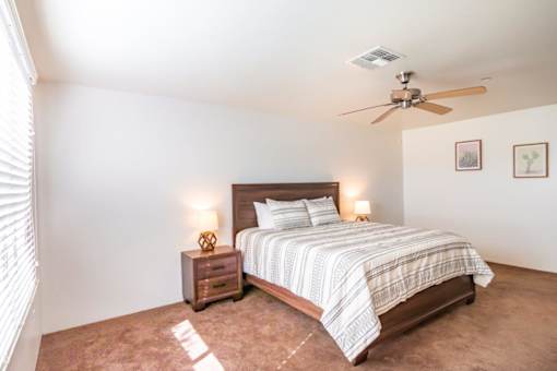 A bedroom with a bed, nightstand, and a ceiling fan.